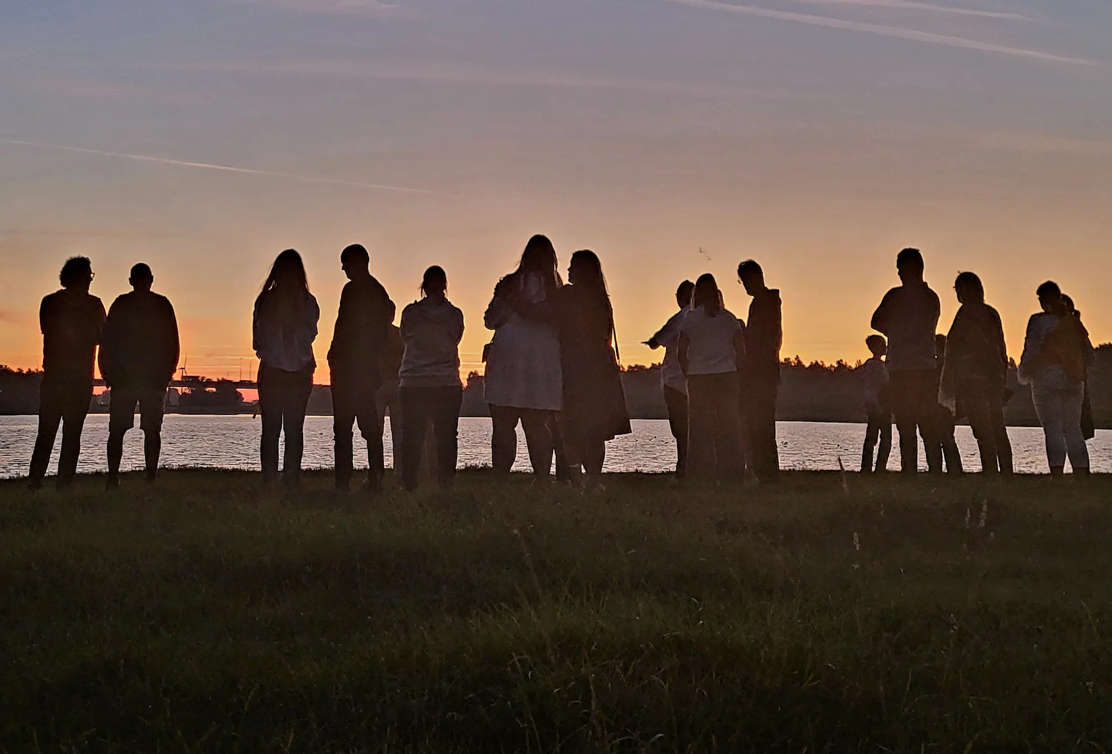 Op de foto een groep mensen die meededen aan Walk into the Light. Ze staan op een grasveld bij de zonsopgang