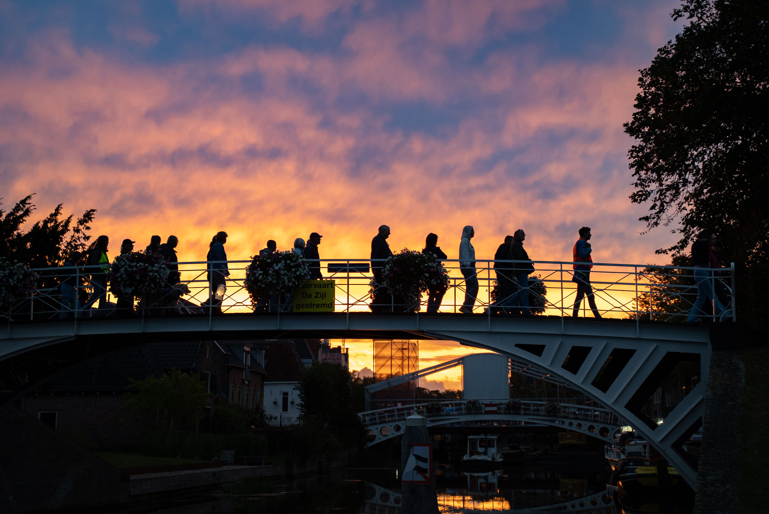 Walk into the Light Dokkum 2025, schaduwen van wandelende mensen op een brug bij zonsopkomst